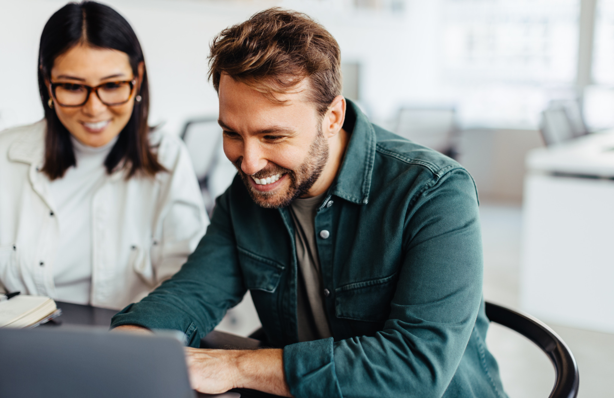 Successful business man using a laptop in a meeting with his colleague. Happy business man playing a slideshow presentation in an office.