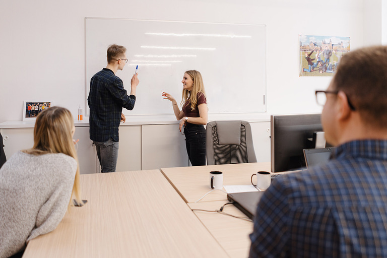 Junger Geschäftsmann mit Kollegen am Whiteboard im Büro